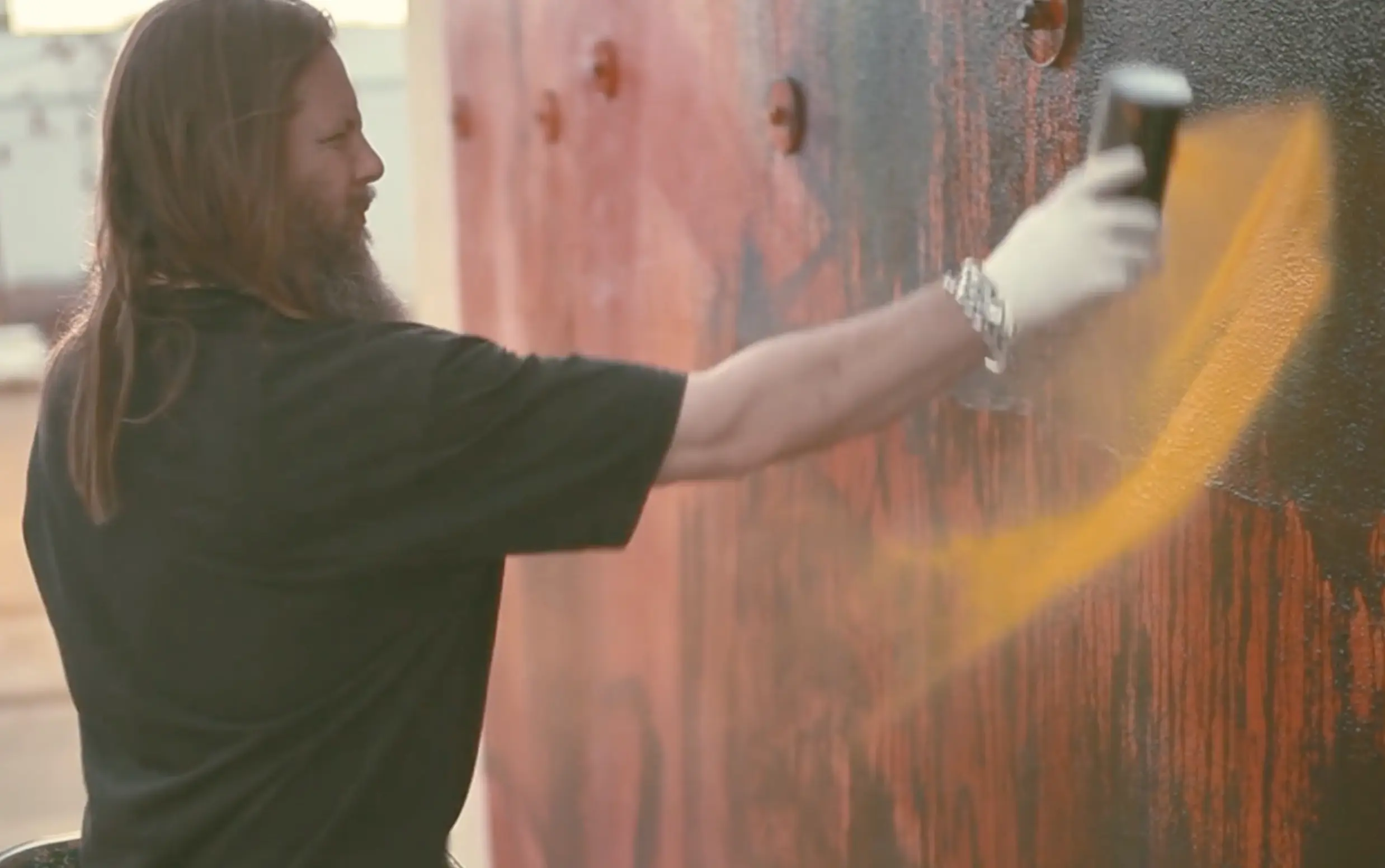 A person spray painting a wall while being filmed by a branded documentary production company in Dallas.