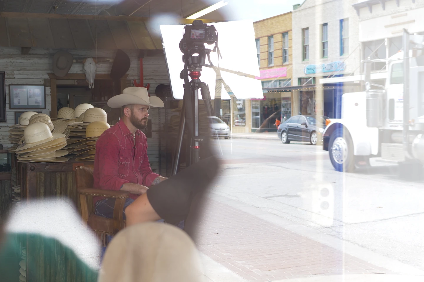 Window reflection of a Biggar Hats team member on set with a video production company in Dallas.