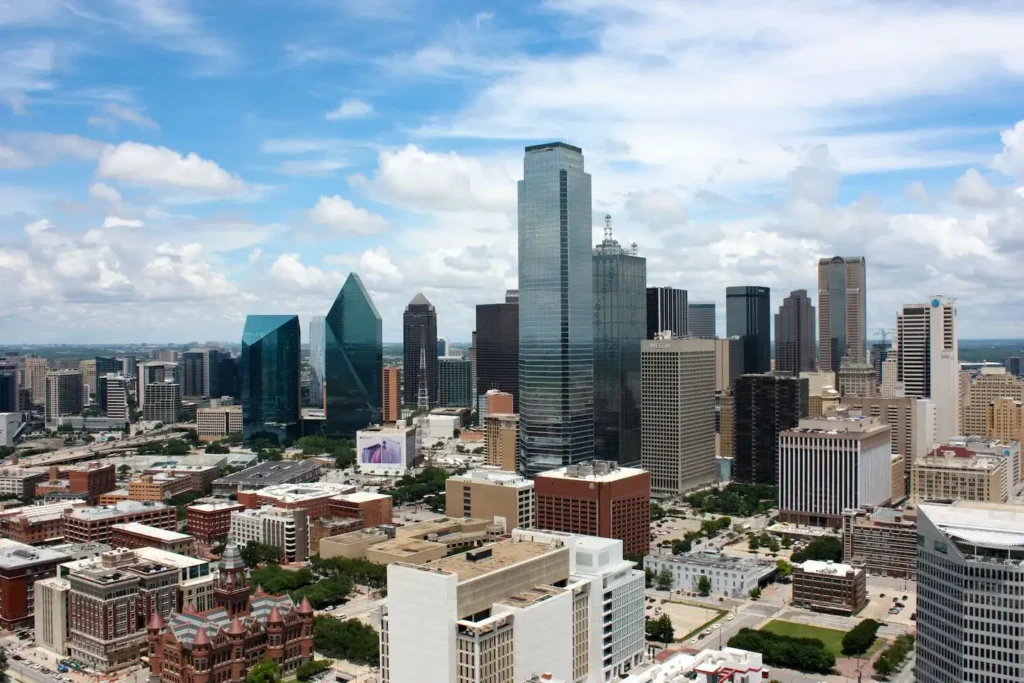 Skyline of Dallas, Texas during the day with a cloudy blue sky in the background.
